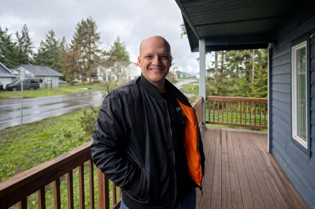 Smiling man standing on wooden porch.